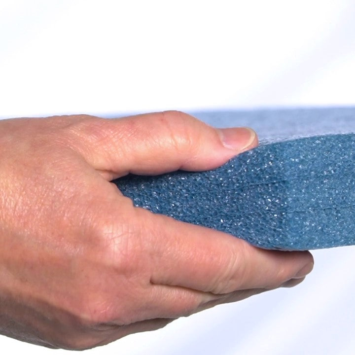 hand squishing sagsaway foam board to show its compression